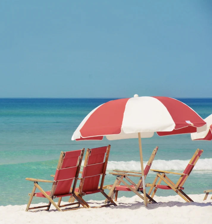 A sunny beach scene with umbrella and chairs on soft sand
