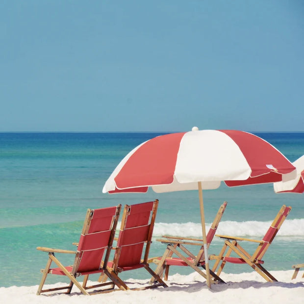 A sunny beach scene with umbrella and chairs on soft sand
