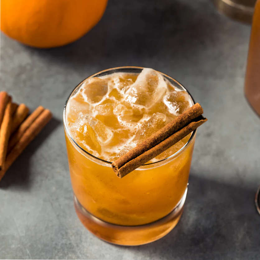 Pumpkin spice latte with cinnamon stick on a dark surface