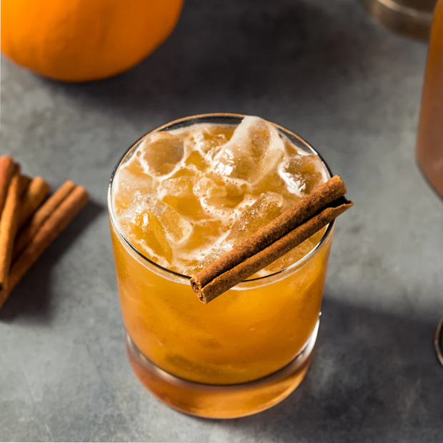 Pumpkin spice latte with cinnamon stick on a dark surface