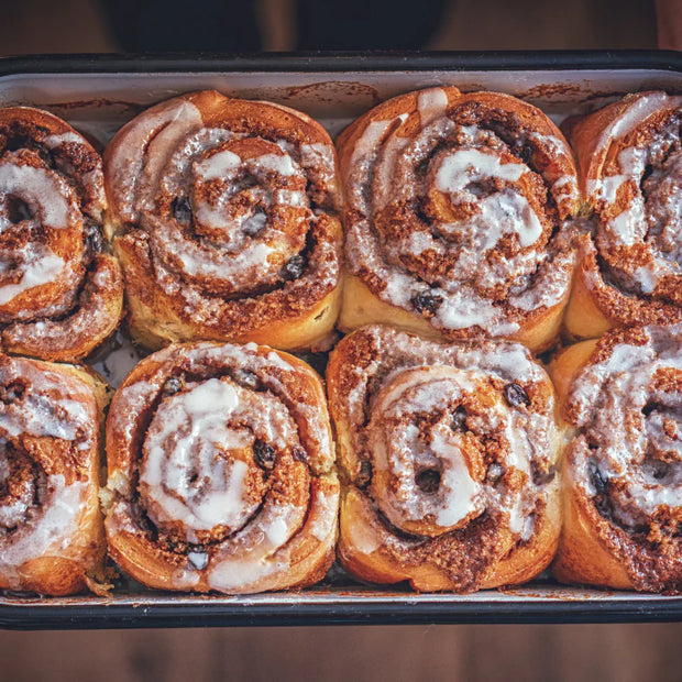 Baked cinnamon rolls with icing in a baking tray