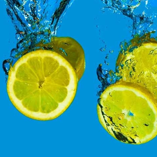 Lemons being dropped into water with a blue background