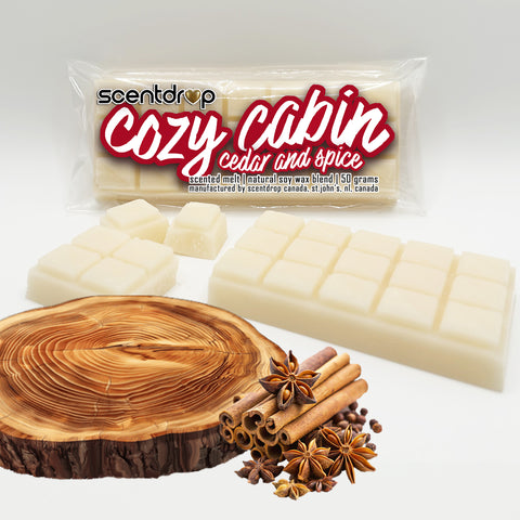 Scentdrop 'Cozy Cabin' cedar and spice scented wax melts in a clear plastic bag, shown with several off-white wax melts and a large wax melt bar in front, alongside cinnamon sticks, star anise, and a wood slice on a white background.