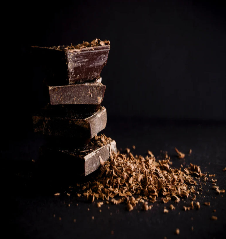 Stack of dark chocolate bars with some broken pieces on a dark background