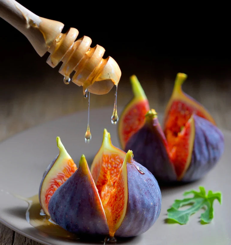 Honey dripping on two figs on a grey plate.
