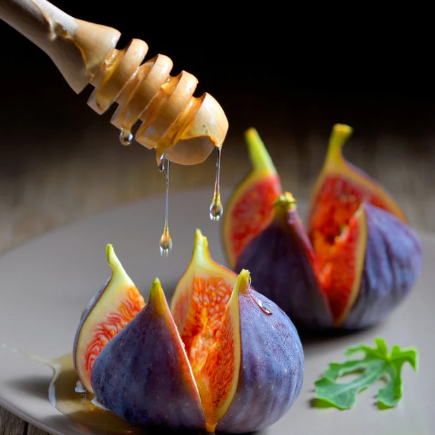 Honey dripping on two figs on a grey plate.