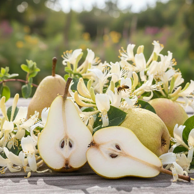 Fresh pears, including one cut open to show the interior, arranged on a wooden surface with white flowers in a garden setting.