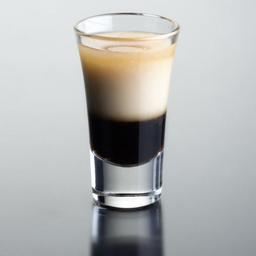 Two-toned shot glass with black and white liquid on a gray background