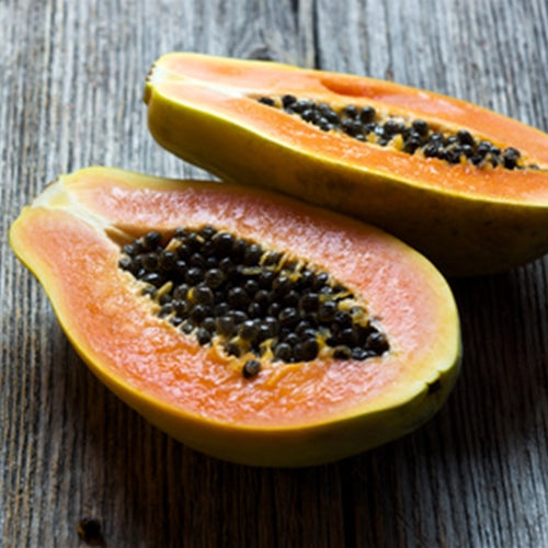Two halves of a papaya on a wooden surface