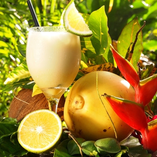 Tropical drink with coconut and fruit on a green leafy background