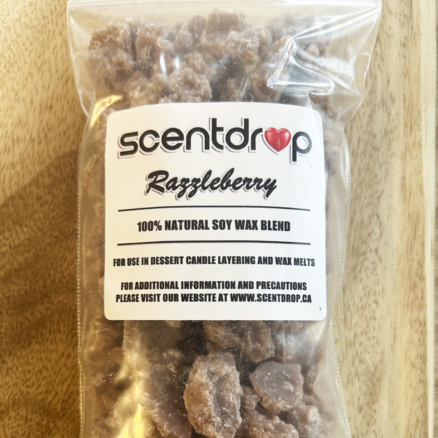 Scentdrop Razzleberry soy wax blend in a clear package on a wooden surface