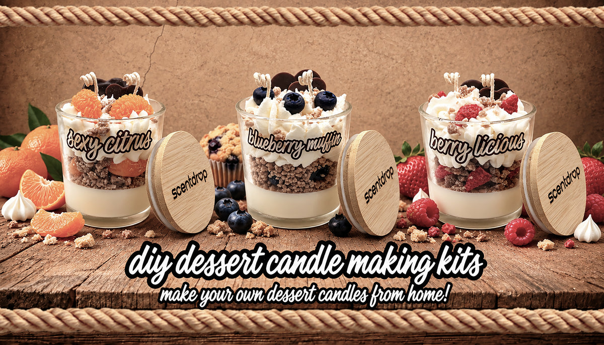 Three DIY dessert candle making kits by Scentsy are displayed on a rustic wooden table. Each kit includes a glass jar filled with layered dessert ingredients (grain, cream, blueberries, strawberries, orange slices) and a round wooden lid with the scent names 'sexy citrus', 'blueberry muffin', and 'berry picnic' written on them.