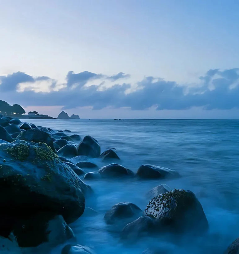 Rocks on a beach with a blue sky and clouds