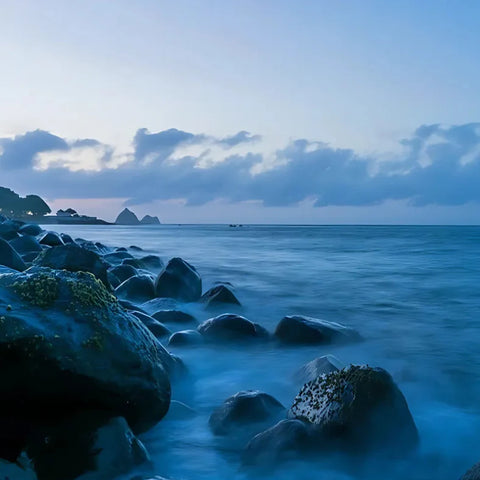 Rocks on a beach with a blue sky and clouds