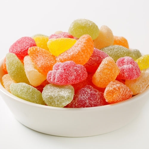 Assorted colorful gummy candies in a white bowl on a white background