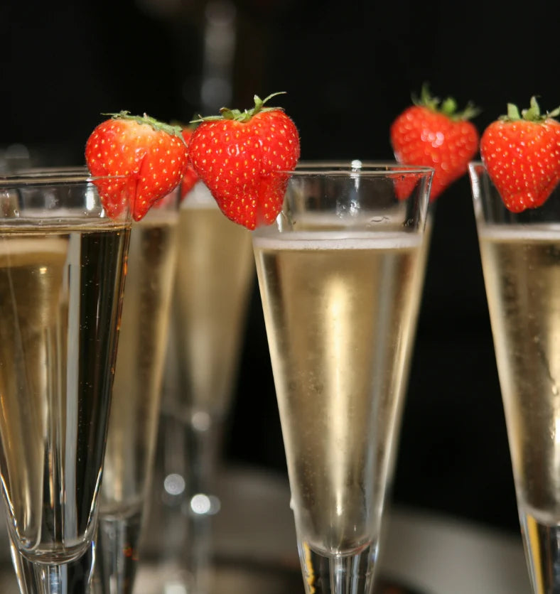 Strawberries on the edge of 5 champagne glasses filled with champagne