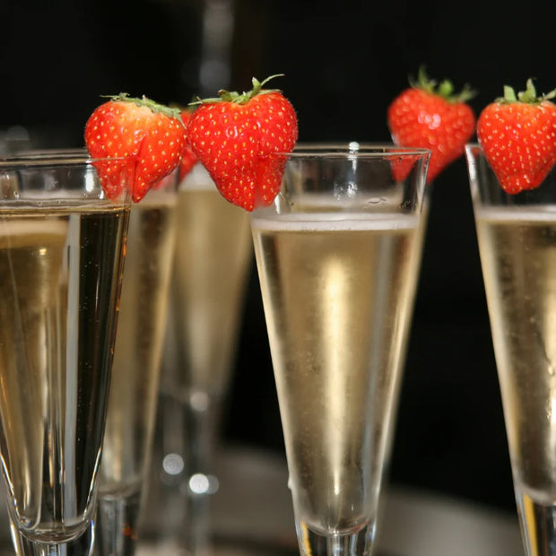 Strawberries on the edge of 5 champagne glasses filled with champagne