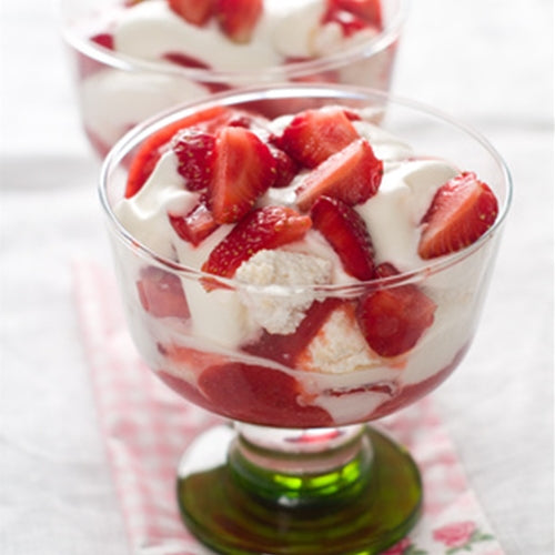 Dessert with strawberries and cream in a glass bowl on a white background