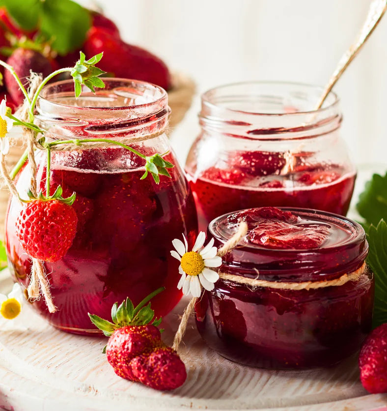 Three jars of strawberry jam with fresh strawberries on a wooden surface